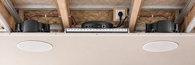 Fotorealistische Anwendungsvisualisierung: DAN-AMP-100 und zwei separat erhältliche passive Deckeneinbaulautsprecher. Einbau nur gemäß Geräteanleitung und örtlichen Sicherheitsvorgaben.